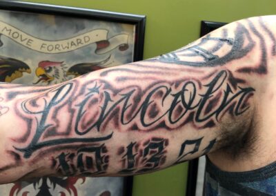 Fresh black and grey script lettering forearm tattoo completed at Clockwork Tattoo Shop in Centereach, Long Island, New York.